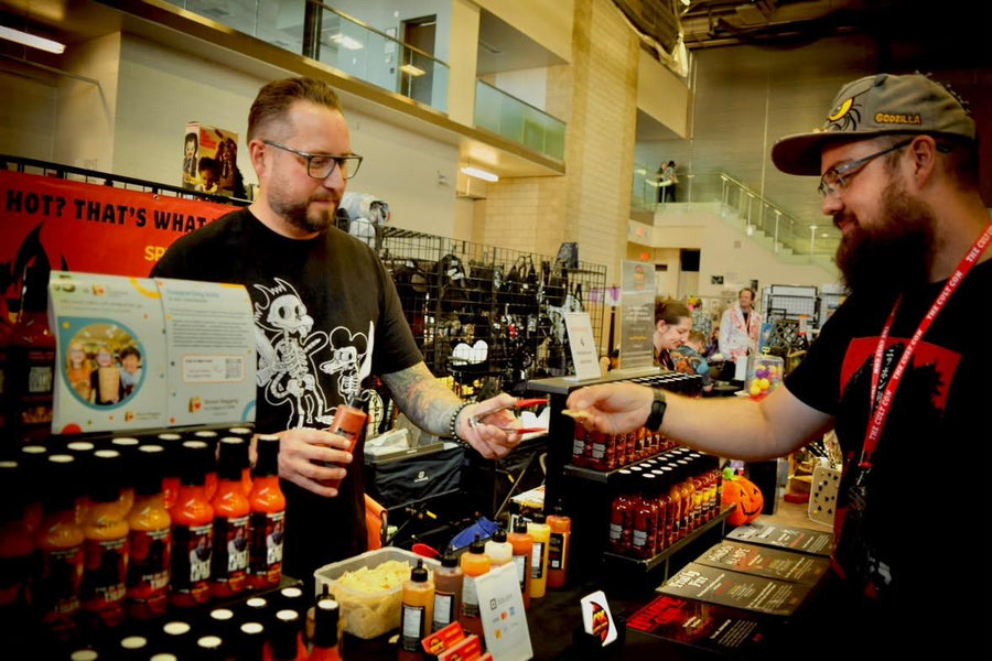 Andy Knox handing a customer a bottle of hot sauce at a market