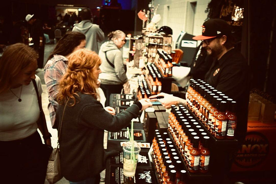 Customers sampling Knox Your Socks Off hot sauce at a market booth